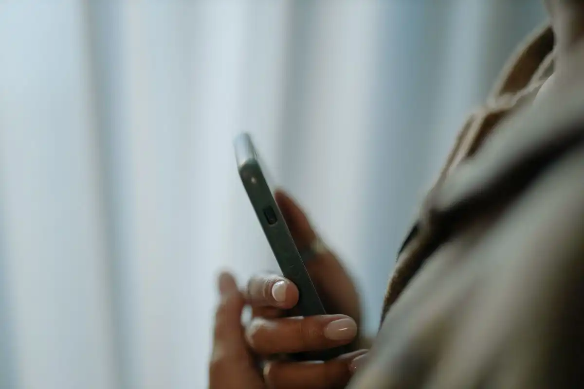 Mano sosteniendo un teléfono en penumbra